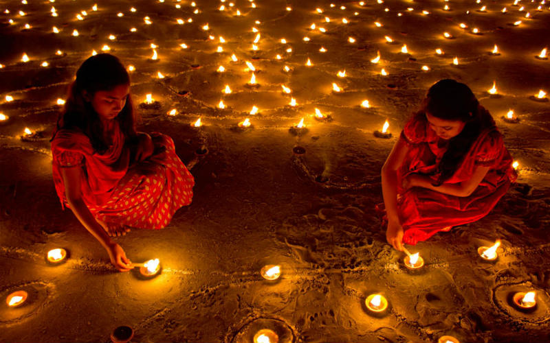 Women lighting candles during Diwali
